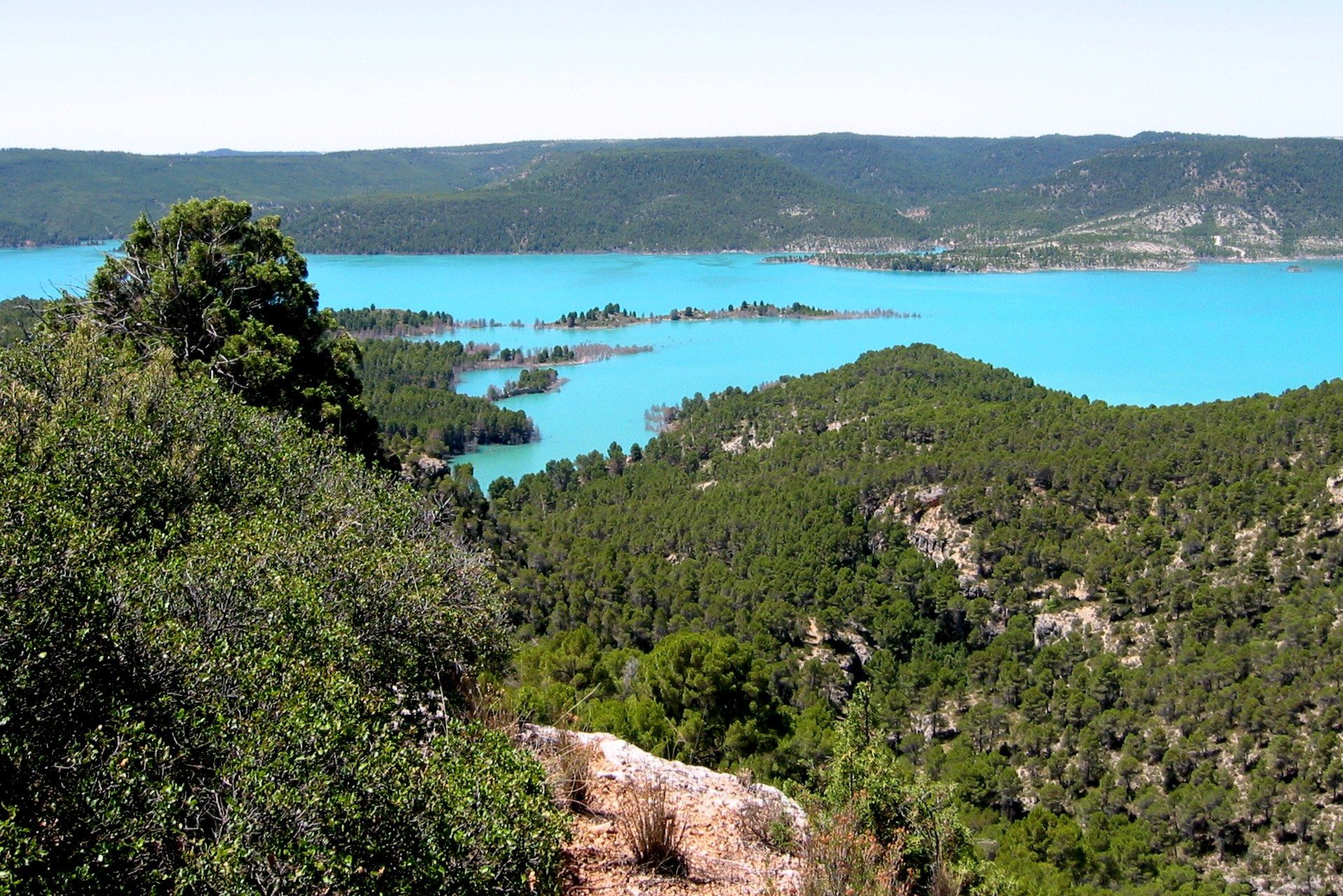El embalse de Contreras, de agua turquesa, encajado entre laderas de pinar.